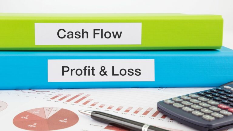 Is cash flow more important than profit: graphs on paper, a calculator and a pen, and filing books on the table.