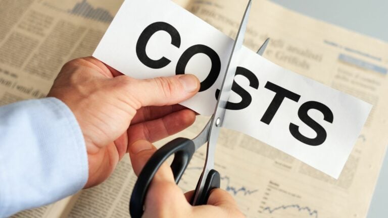 What are the characteristics of cost cutting - a person cutting a paper labeled "costs" with a pair of scissors.